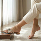 Person wearing a sandal on a wooden block with a neutral background