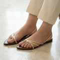 Beige sandals worn with beige pants on a light wooden floor